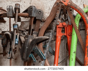 Collection of old, rustic hand tools and equipment hanging on a wall in a traditional workshop