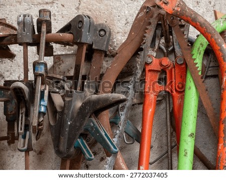 Collection of old, rustic hand tools and equipment hanging on a wall in a traditional workshop