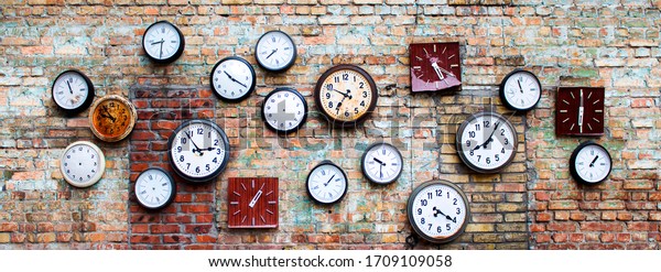 collection of old, vintage, hinged watches, all clock show different times, some do not have insoles, they all hang on an old brick wall, bricks changed color from time to time