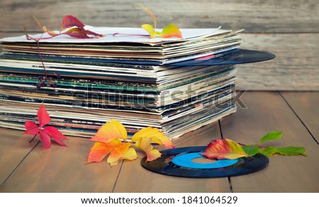 Collection of old vinyl records in a stack with autumn leaves.
