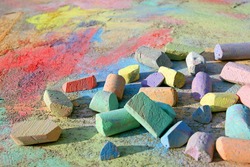 A Collection Of Rainbow Colored Sidewalk Chalk Is Scattered On The Pavement Outside, On Top Of A Bright, Colorful Drawing