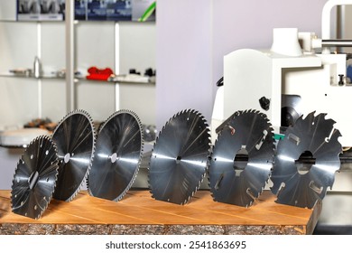 A collection of sharpened circular saw blades rests on a wooden surface, showcasing their distinct sizes and types. The workshop background highlights a focus on craftsmanship and precision. - Powered by Shutterstock