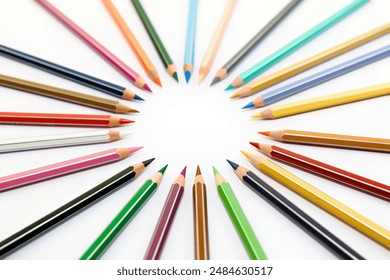 A collection of sharpened colored pencils are arranged in a circle on a white surface. The pencils are all different colors and are arranged with their tips pointing towards the center of the circle. - Powered by Shutterstock