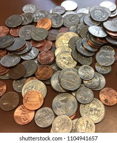 Collection of shiny US coins; quarters, nickels, and dimes spread  out on a table