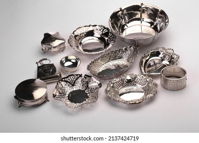 A collection of silver and silver plater items including dishes, flatware and others. Photographed on a light background