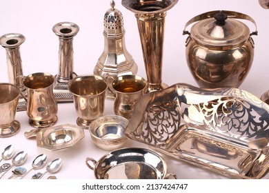 A collection of silver and silver plater items including dishes, flatware and others. Photographed on a light background