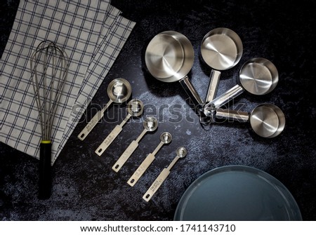 Collection of stainless  measuring cups and measuring spoon with a plate in top view