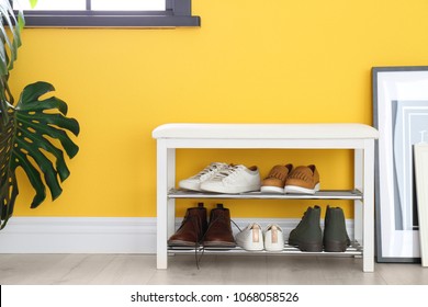 Collection of stylish shoes on rack storage near color wall in room