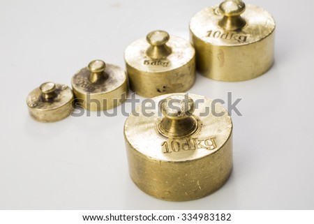 Collection of Thee Vintage Golden And Silver Calibration Weights on White Background