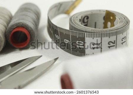 A collection of threads, sewing meters and thread cutters, gray themed sewing tools.