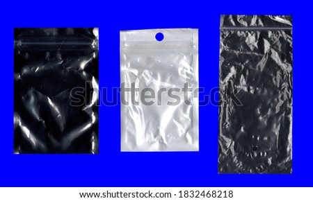 A collection of three different blank plastic bags (black, white, semi-transparent), used to protect small electronic items before shipping or selling. Isolated on a blue surface.
