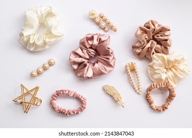 Collection of trendy silk elastic band scrunchies and pearl hair clips on white background. Diy accessories and hairstyles concept, luxury color
