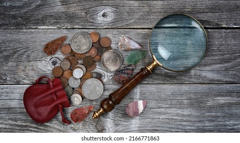 Collection Of United States Rare Coins And Native American Arrowheads With Antique Magnifying Glass On Rustic Wood Background 