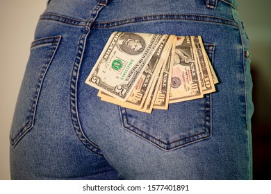 A collection of US dollars in a female jeans pocket, bit of pocket money, close up to 50 dollars. American dollars stuck in woman pocket. The dollar the world currency. fifty dollar and twenty dollars