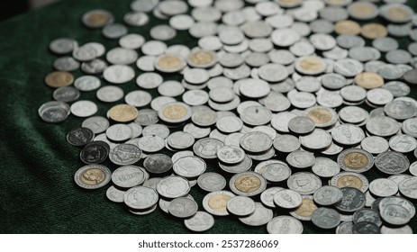 collection of various coins scattered on green surface, showcasing different sizes and designs. shiny metallic surfaces reflect light, creating interesting visual texture. - Powered by Shutterstock