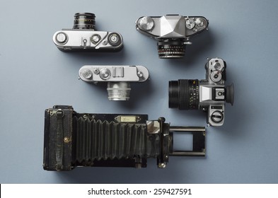 Collection of vintage cameras and camera lens well organized over blue background, top view