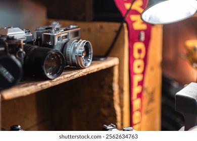 A collection of vintage cameras displayed on a wooden shelf, accompanied by a college banner, creating a nostalgic ambiance ideal for photography lovers appreciating retro charm and design. - Powered by Shutterstock