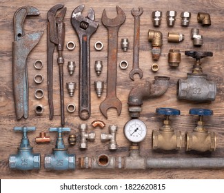 Collection of vintage plumber's tools, valves and other equipment on old wooden background, top view