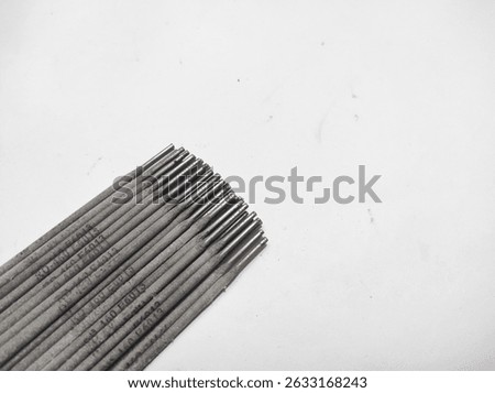 A collection of welding electrodes, featuring cylindrical rods with metallic tips and a gray flux coating.