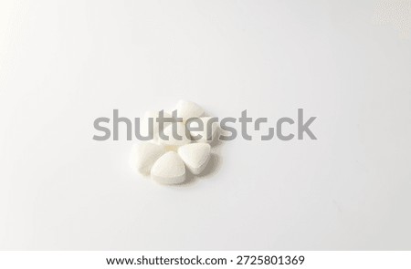 A collection of white, triangular-shaped medicinal tablets on a white background. Illustration of health, medication, pharmacy, medicine, taking medication, tablet dosage forms.
