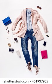 Collection Of Women's Clothing And Accessories. Overhead Of Essentials Young Woman. Outfit Of Casual And Elegant Woman, Jeans, High Heels Shoes, Pink Coat, Handbag, Notebook, Telephone, Sunglasses.