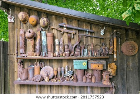 Collection of World War II artifacts recovered from the Courland Pocket battlefield, displayed on a wooden wall. Rusted relics preserve wartime history