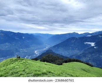 A collective view of wide Kullu Valley, meandering river, lush green alpine meadow and Himalaya mountain range with cloudy sky. Captured during Kalihani Pass trek near Manali Himachal Pradesh,India. - Powered by Shutterstock