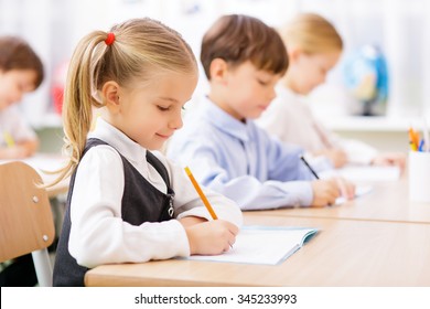 Collective work. Little pupils are all busy writing in their copybooks. - Shutterstock ID 345233993