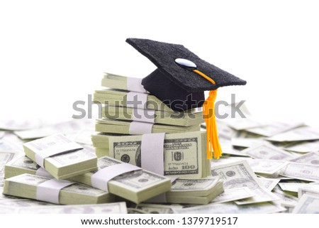 College Admissions Scandal: Mortarboard on a pile of money representing the high cost of education, Student Loans and bribery. Bills are Stage Money.