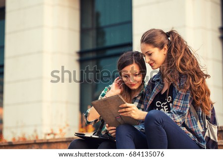 College friends having a good time after class. Girls looking at tablet while discussing. Back to school concept.