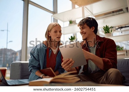 College friends using touchpad while studying together at campus. 