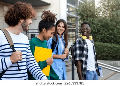 College friends walk to class together. Multiracial university students in campus talk and have fun outdoors. - Shutterstock ID 2265333781