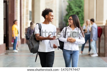 College friends walking in campus and talking, having break after classes