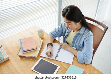 College Girl Doing Homework At Her Desk, View From Above