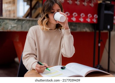 College Girl Drinking Coffee While She Is Reading For College In The Study Room