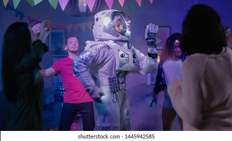 At The College House Costume Party: Fun Guy Wearing Space Suit Dances Off, Doing Robot Dance Modern Moves. With Him Beautiful Girls And Boys Dancing In Neon Lights.