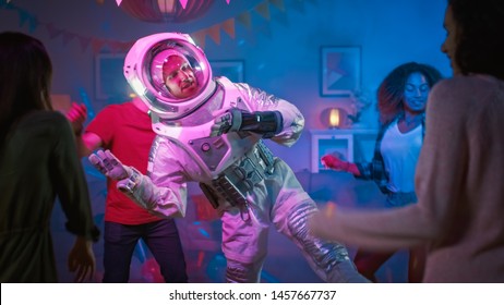 At The College House Costume Party: Fun Guy Wearing Space Suit Dances Off, Doing Robot Dance Modern Moves. With Him Beautiful Girls And Boys Dancing In Neon Lights.