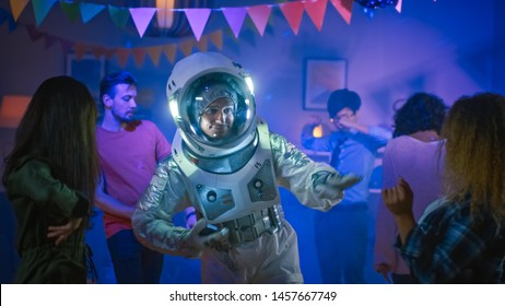 At The College House Costume Party: Fun Guy Wearing Space Suit Dances Off, Doing Robot Dance Modern Moves. With Him Beautiful Girls And Boys Dancing In Neon Lights.