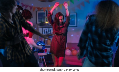 At The College House Party: Young Girl Dances In The Middle Of A Circle Of People. Diverse Group Of Friends Have Fun, Dancing And Socializing. Disco Neon Strobe Lights Illuminating Room.