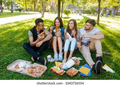 College Mates Are Eating Outdoors. Students Enjoying Pizza, Noodles And Other Fast Food In The Campus. Lunchtime Concept.