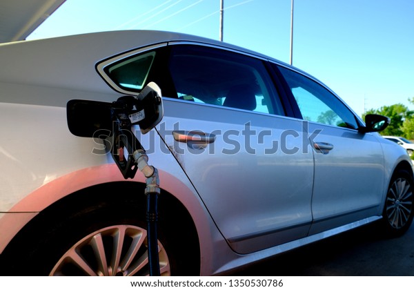 College Station, Texas / USA - March 26 2019: Fuel\
nozzle in fuel tank opening; gassing up car; nozzle and hose at a\
gas station. 