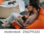 A college student is engaged in playing the guitar during a music class, showcasing learning and creativity. The relaxed environment promotes concentration and musical expression.