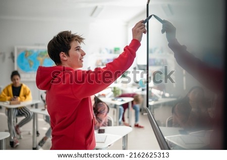 College student explaining some ideas on a touch TV in classroom.