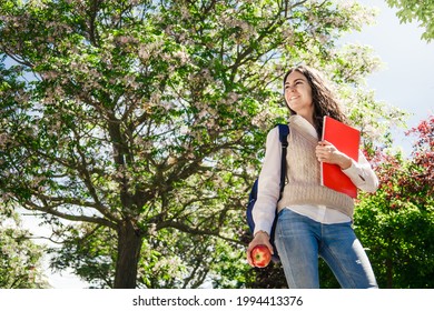 College Student Girl Eating An Apple In Campus. Shot From Below And Copy Space