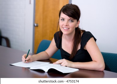 College Student Refers To The Catalogue While Filling Out Paperwork