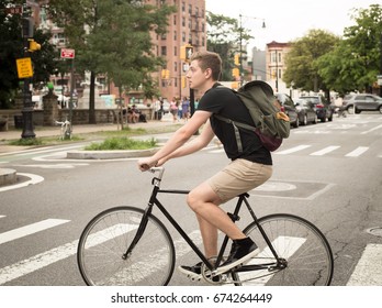 College Student Riding Bike Crossing The Crosswalk In The City, Photographed In Brooklyn, NY In July 2017