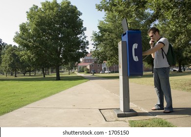 College Student Using Campus Payphone.  Open Laptop Sitting On Phone Booth.