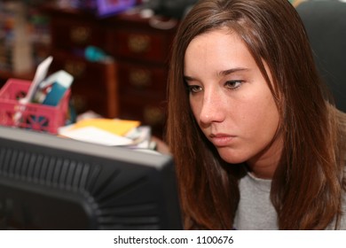 College Student Working At Computer In Messy Dorm Room, Concentrating