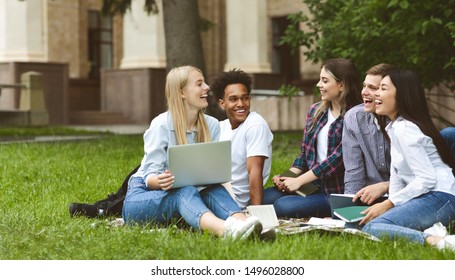 College students having discussion in campus, sitting on grass, preparing for exams
