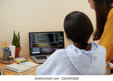 College students reviewing lines of programming code on laptop screen and searching for mistakes